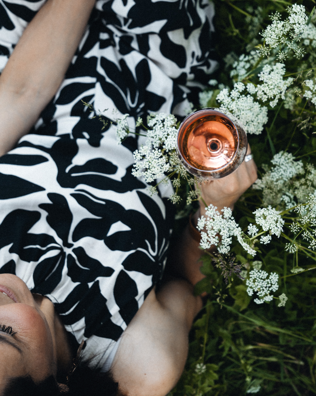 Weinblüten-Winzerin Claudia Fischer-Gangl liegt in einer Blumenwiese und genießt Rosi - den Rosé-Wein der Weinblüten-Winzerinnen